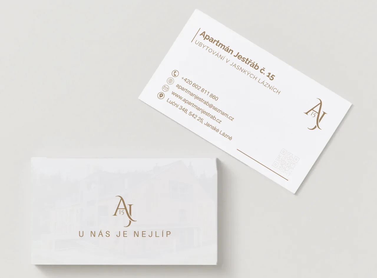 Business cards for Apartment Jestrab: a white front with the gold AJ15 monogram and the tagline U nás je nejlíp, and a back with the apartment's contact details and a QR code.